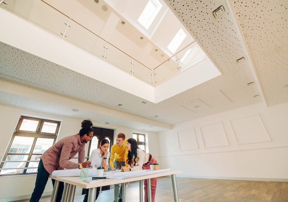 Professional multiracial team of male and female engineers or architects having a meeting and brainstorming together over a building project they are working on while gathered around the table.